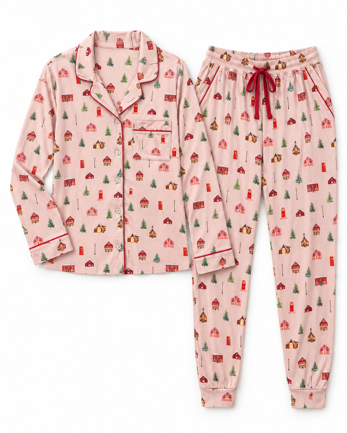 A two-piece pajama set featuring a light pink long-sleeve button-front top with a red collar and cuffs, and matching jogger pants with an elastic drawstring waist, both covered in a small red and green holiday house and tree print.
