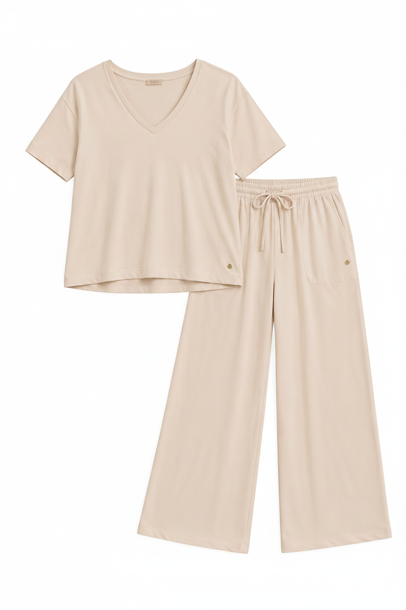 A two-piece loungewear set in a light cream-beige color, featuring a short-sleeve V-neck top and matching wide-leg drawstring pants, laid flat on a solid beige background.