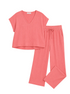 A two-piece loungewear set in a ribbed coral pink fabric, featuring a short-sleeve V-neck top and matching drawstring pants, laid flat on a light off-white background.